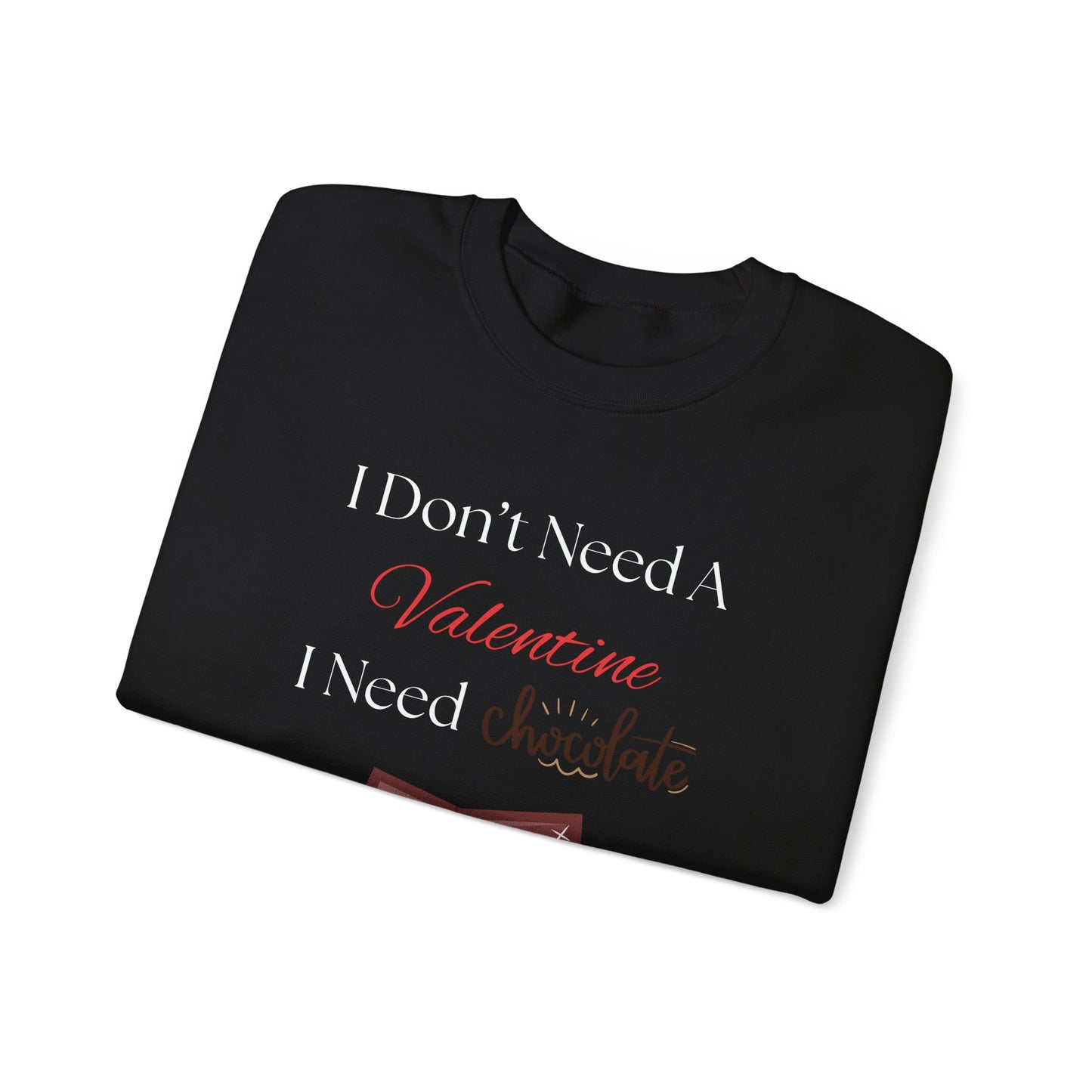 A folded black Valentine’s sweatshirt with the phrase “I Don’t Need a Valentine, I Need Chocolate” printed on the front in red, white, and brown lettering.