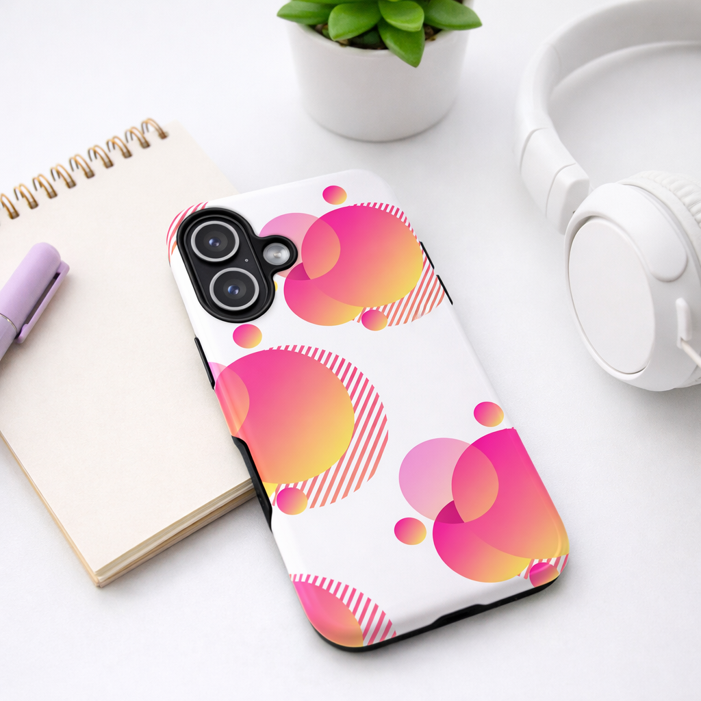 Pink gradient geometric phone case with abstract circle design, styled on a modern desk with a notebook, headphones, and a small plant for a youthful aesthetic.