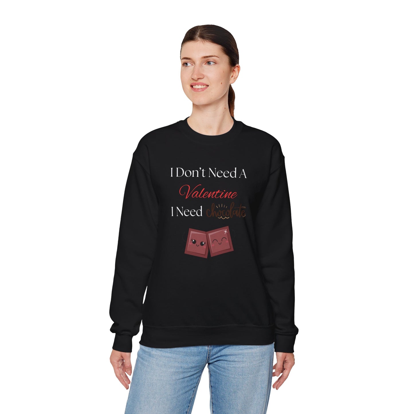 A woman wearing a black Valentine’s sweatshirt that says “I Don’t Need a Valentine, I Need Chocolate,” with two cute smiling chocolate characters printed on the front.