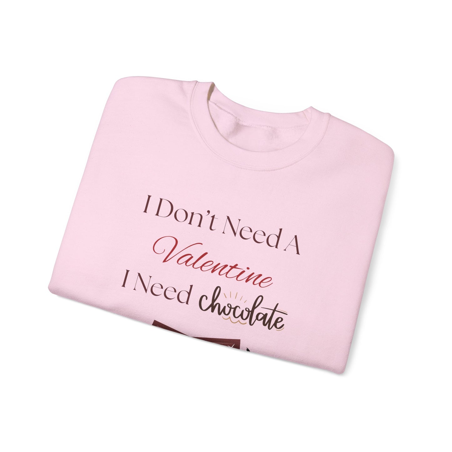 A folded pink Valentine’s sweatshirt with the phrase “I Don’t Need a Valentine, I Need Chocolate” printed on the front in red, white, and brown lettering.
